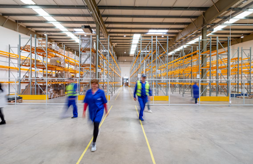 Warehouse workers walking through storage aisles with pallet racks