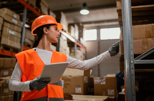 Woman inspecting storage racks in safety gear