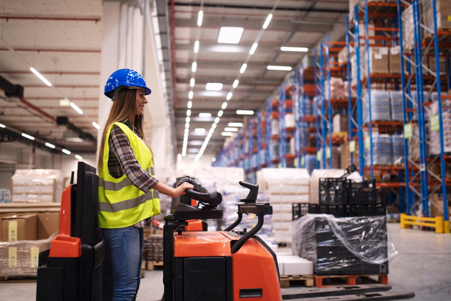 Woman warehouse worker operating forklift machine